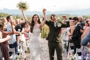 Bride and groom walking down outdoor aisle